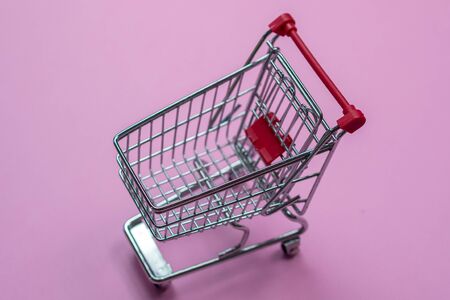 closeup of small miniature shopping cart taken from above on pink backgroundの写真素材