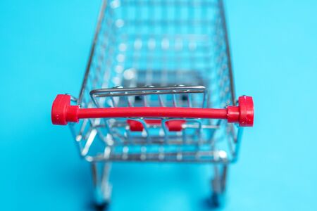 closeup of small miniature shopping cart taken from above on blue backgroundの写真素材