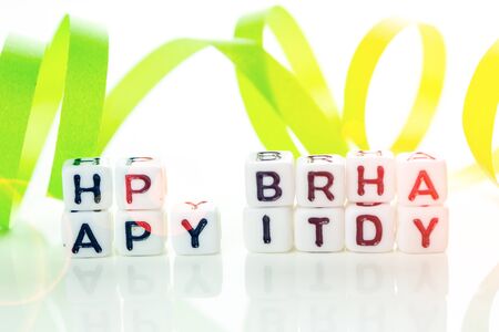 happy birthday special unconventional card made of white cubes with black letters and green birthday decorations on white backgroundの写真素材
