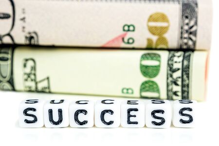 success concept, american dollar banknote blocks in all denominations in one row on white background with the word success made of little white cubesの写真素材