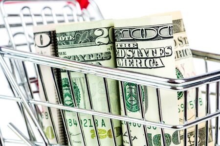 silver shopping trolley full of american dollars on white backgroundの写真素材
