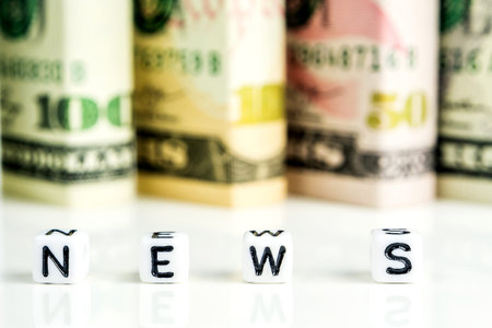 little white cubes with black letters of word news on white background with american dollars in the...