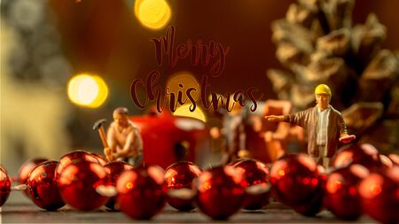 closeup of Christmas decorations, jingle bells and little miniature figurines with orange colored blurred lights and evening warm atmosphere and dusk backgroundの写真素材