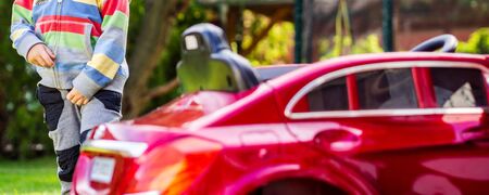 little boy is driving his electro toy car on the backyard of his parent's house, action that makes every little boy really happyの写真素材