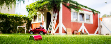 little boy is driving his electro toy car on the backyard of his parent's house, action that makes...