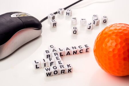 little white dices with black letters forming a crossword with the theme work life balance as equilibrium of professional and personal family life with tools on white backgroundの写真素材
