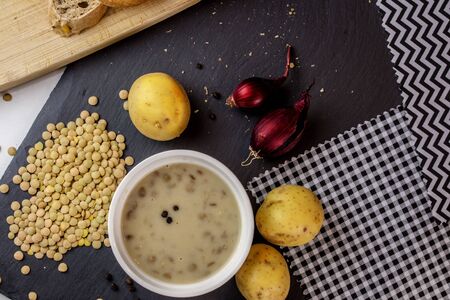 homemade closeup creamy brown lentil soup from above with ingredients on textured black backgroundの写真素材