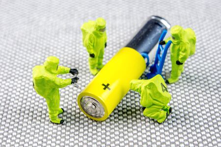 closeup of miniature figurines dressed like members of firemen special team interfering during gas and other chemical accidents, diagnosting little recharchable alkaline recharchable AA batteryの写真素材