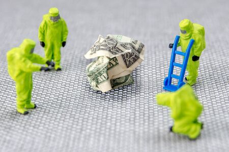 closeup of miniature figurines dressed like members of firemen special team interfering during gas and other chemical accidents with the action protecting/saving american dollar, the debt is rising without controllの写真素材