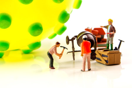 closeup of big corona virus with a team of miniature figurines of workers preparing for taking...