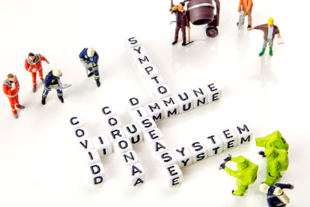the title made of miniature white dices with black letters of very dangerous deadly corona virus type on white background, crosswords with the theme of disease and immune system with miniature figurinesの写真素材