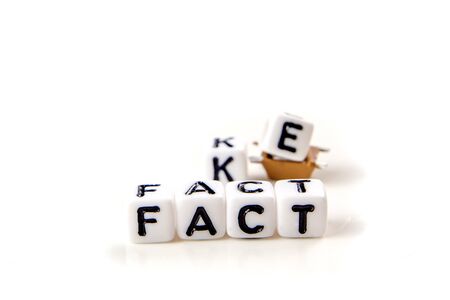 fake and fact text formed of white dices with black letters on white background, how can you distinguish between credible information and fake news, critical thinkingの写真素材