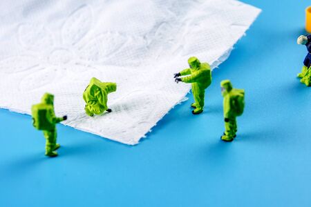 a team of miniature figurines checking a cleanliness of toilet paper, very important to make a desinfection of lavatory and other possibly dirty places in an householdの写真素材