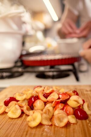 young boy is cooking and baking cherry pie with almond slices with his mammの写真素材