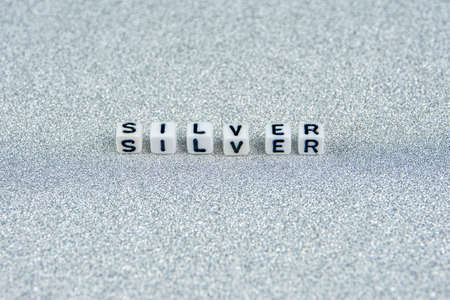 silver word formed by white dices with black letters  laying in the middle part of silver backgroundの写真素材