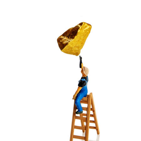everybody wants to have gold savings these days, a painter miniature figurine on a ladder finalizing a painting of golden rock in the air or fake gold conceptの写真素材