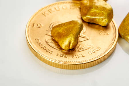 golden south african krugerrand one ounce coin laying on a heap of golden nuggets, golden ore on white background isolated with plenty copy spaceの写真素材