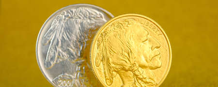 silver and golden american buffalo one ounce coins laying on silver and golden background, image split in two halvesの写真素材