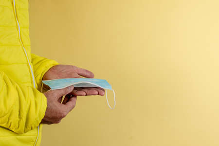 man in yellow jacket is using a protective mask against corona virus on yellow background, high alert and the battle against the disease, COVID-19 SARS, SARS-CoV, virus 2020の写真素材