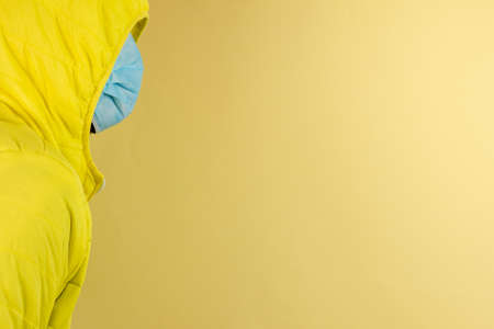 man in yellow jacket is using a protective mask against corona virus on yellow background, high alert and the battle against the disease, COVID-19 SARS, SARS-CoV, virus 2020の写真素材