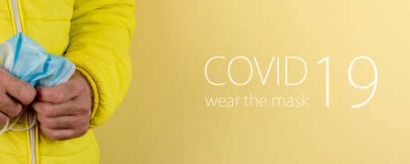 man in yellow jacket is using a protective mask against corona virus on yellow background, high alert and the battle against the disease, COVID-19 SARS, SARS-CoV, virus 2020の写真素材