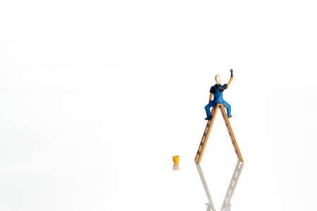 Man standing on a ladder drawing something on white wall, may be used as a foreground for multiple themesの写真素材