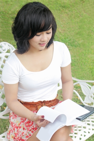 young woman reading book in the parkの写真素材