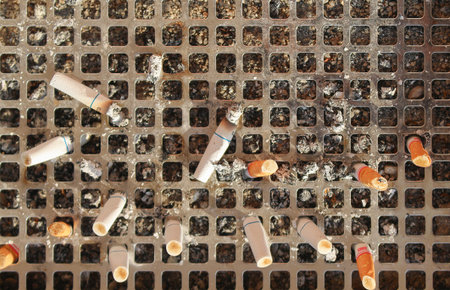 Discarded cigarette butts in a metal public ashtray 