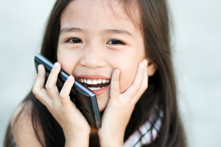 Happy little girl holding a mobile phoneの写真素材