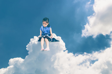 a little girl or student sitting on a cloud and Reading a book.の写真素材