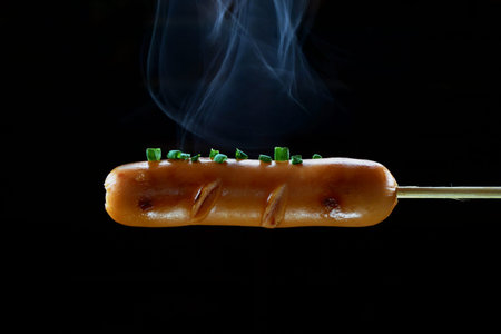 Grilled sausage and smoke on black backgroundの写真素材