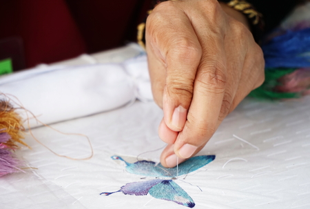 close up hands of seamstress with cloth fabricの写真素材
