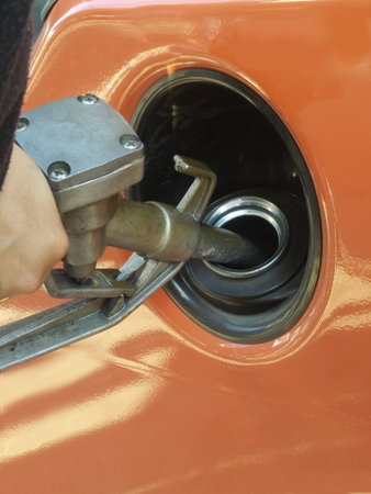 Hand hold the oil filler is processing fuel in carの写真素材
