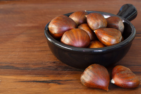 Chestnut in black bowl on wooden tableの写真素材
