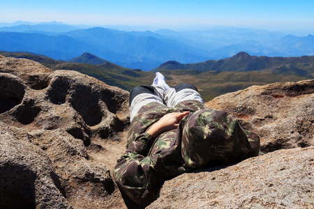 Man laying on edge of mountain peak looking at nature thinking. Selective focusの写真素材