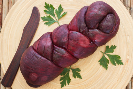 Treccia - braided Mozzarella cheese bundle marinated in red wine on cutting board with knife....