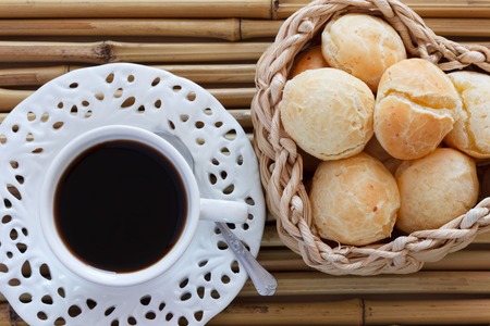 Brazilian snack pao de queijo (cheese bread) on white plate with cup of coffee on bamboo table. Selective focusの写真素材