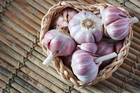 Garlic in wicker basket (heart shape) on wooden table. Selective focus. Copy spaceの写真素材