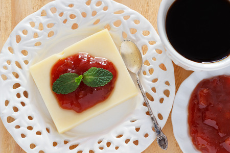 Brazilian dessert Romeo and Juliet, goiabada jam and cheese on white vintage plate with cup of coffee on wooden table. Selective focusの写真素材