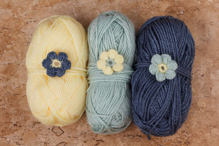 Handmade colorful crochet flower with skein on marble table. Selective focus