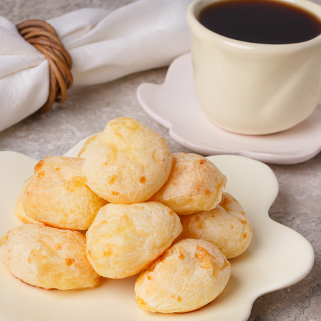 Brazilian snack pao de queijo (cheese bread) on white plate with  cup of coffee on marble table. Selective focusの写真素材