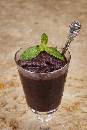 Acai pulp in glass with fresh mint and muesli on marble table. Selective focusの写真素材