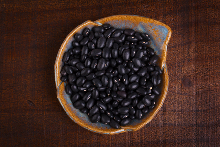 Black beans in bowl on wooden background. Selective focusの写真素材