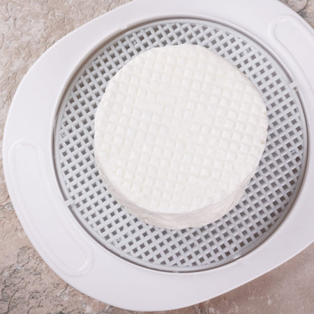 Wheel of brazilian traditional cheese Minas on plate on marble table. Selective focusの写真素材