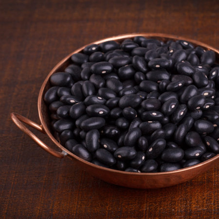 Black beans in bowl on wooden background. Selective focus