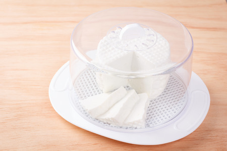 Wheel of brazilian traditional cheese Minas on plate on wooden table. Selective focusの写真素材