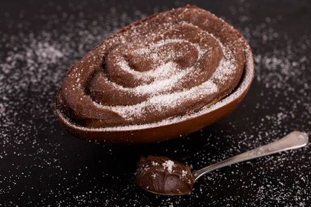 Chocolate egg with filling of brigadeiro for Easter on blackの写真素材