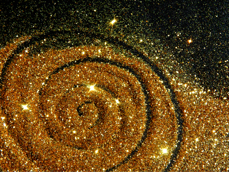 Blurry golden spiral of glitter sparkle on black background like a star galaxyの写真素材