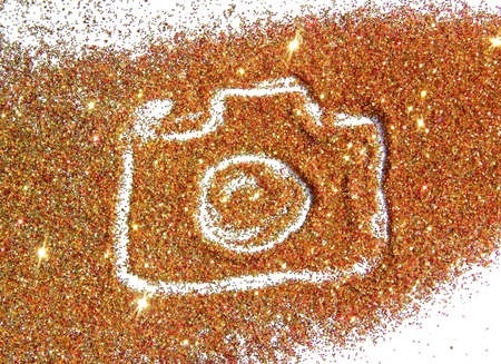 Blurry Photo Camera on golden and red glitter sparkle on white backgroundの写真素材