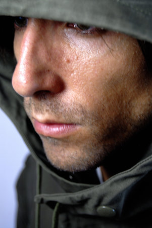 Handsome young man with a beard, hooded, surprised and sad